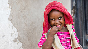 Ein Mädchen trägt einen Pullover über den Kopf und lacht mit offenem Mund in die Kamera.