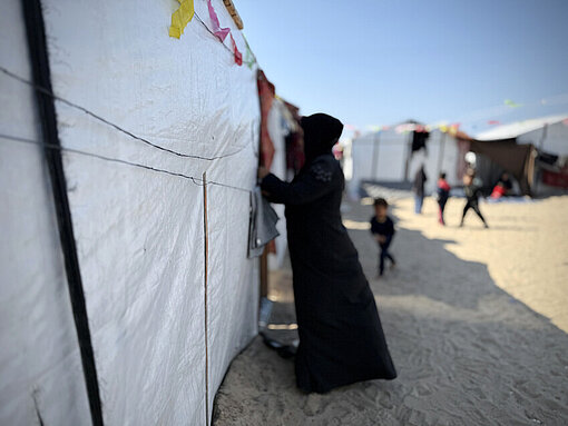 Latifah lebt mit ihren Kindern in einem Zelt in Rafah Mutter aus Gaza steht in schwarz gekleidet an einer Zeltwand