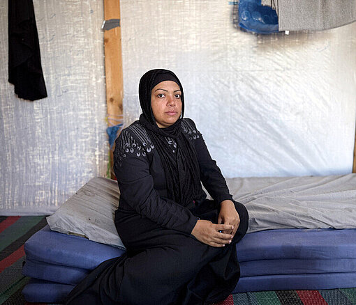 Latifah in ihrem Zelt in Gaza Mutter aus Gaza sitzt in schwarz gekleidet in einem Zelt auf einer Matratze
