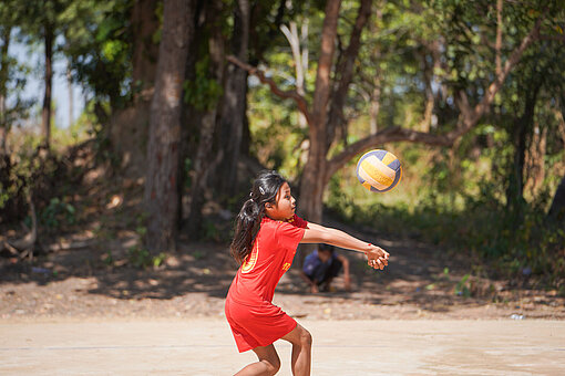 Ein Mädchen in rotem Trikot nimmt einen Volleyball an