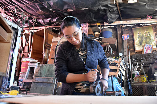 Frau sägt eine Holzplatte mit einer Kreissäge 