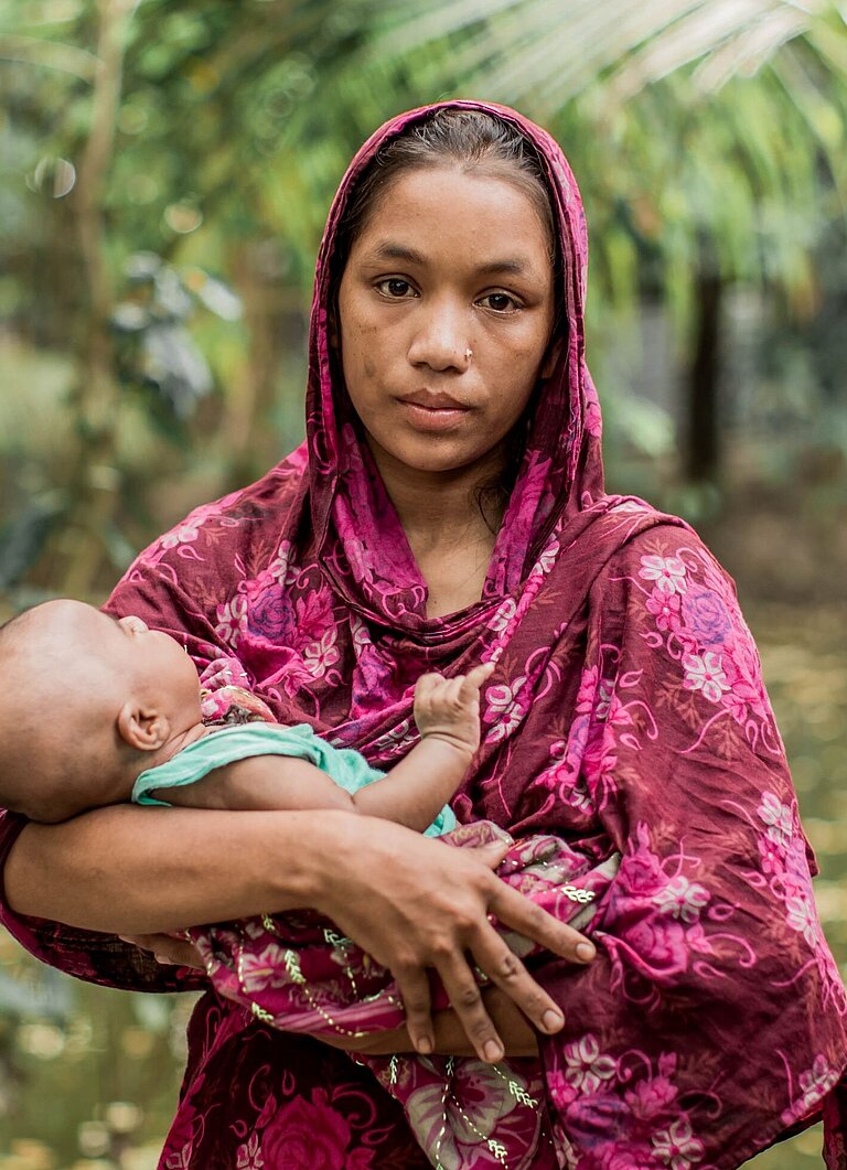 Sumi hält ihr Baby Nusrat im Arm, sie sieht traurig in die Kamera