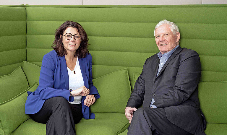 Die Vorstandsvorsitzende Petra Berner und der Präsidiumsvorsitzende Hanns-Eberhard Schleyer sitzen auf einem grünen Sofa und unterhalten sich