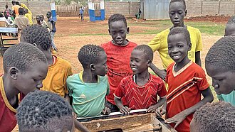 Mehrere Jungen stehen zusammen an einem Fußballkickertisch und lachen