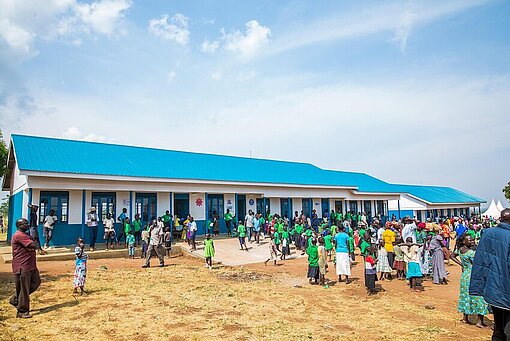 Grundschulkinder haben sich auf dem Schulhof vor ihrem neuen Schulgebäude versammelt