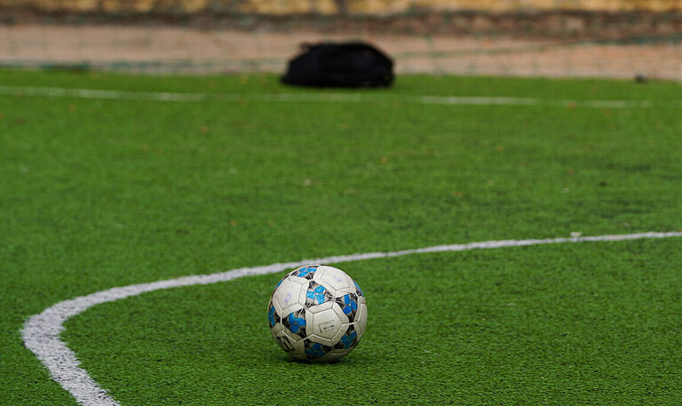 Fußball auf grünem Rasen mit weißer Markierung