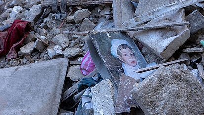 Bild: In den Trümmerteilen eines Wohnhauses liegt ein Bild von einem Kind