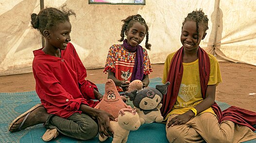 Mädchen spielen mit Kuscheltieren im kinderfreundlichen Raum von Plan im Transitzentrum Renk.