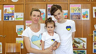 Eine Frau steht zusammen mit ihren beiden Kindern in einem Schutzzentrum für Gefüchtete in Bukarest, Rumänien