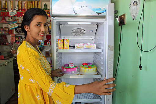 Eine junge Frau am offenen Kühlschrank