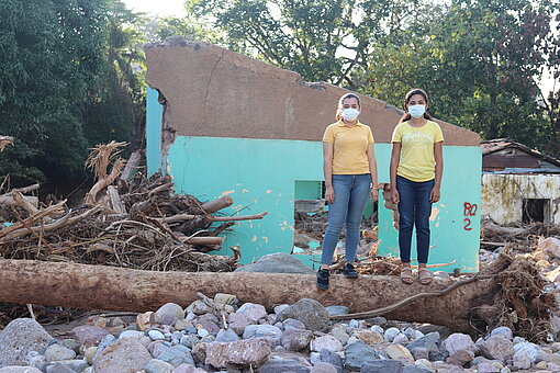 Zwei Mädchen stehen vor einem zerstörten Haus im ländlichen Honduras