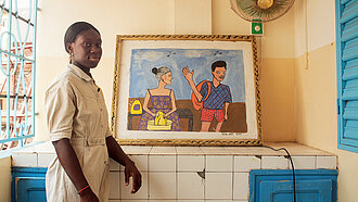 Eine junge Frau steht vor einem gerahmten Kunstwerk
