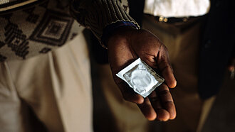 Aufklärung und Verhütungsmittel Eine Person hält ein Kondom in seiner ausgestreckten Hand