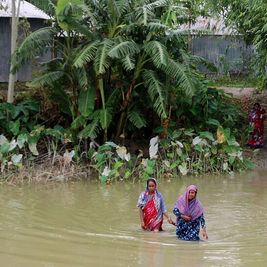 Zwei Frauen waten durch hohes Wasser