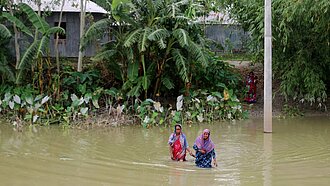 Zwei Frauen waten durch hohes Wasser