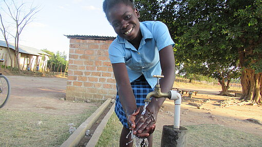 Handwaschstationen für Schulen in Malawi. Eine junge Frau wäscht sich die Hände an einer Handwaschstation.