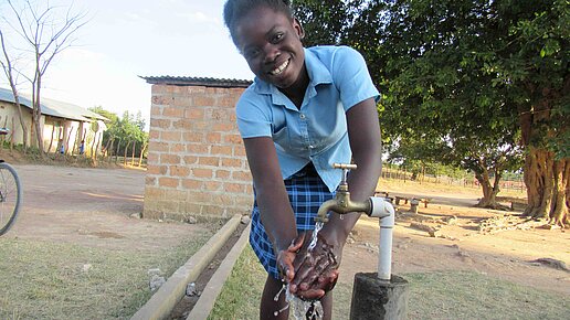 Handwaschstationen für Schulen in Malawi. Eine junge Frau wäscht sich die Hände an einer Handwaschstation.