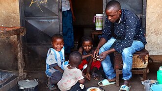 Ein Vater verteilt Essen an drei kleine Kinder