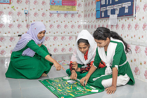 Drei jugendliche Mädchen sitzen auf dem Boden und spielen ein Brettspiel