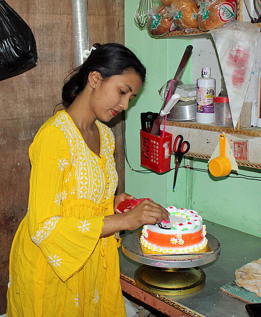 Eine junge Frau verziert eine Torte mit Zuckerguss