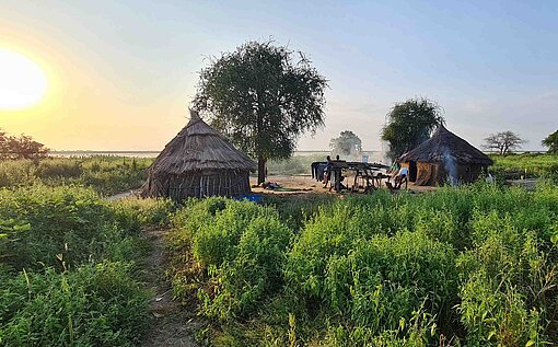 Dorf mit Strohhütten im Sonnenuntergang