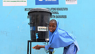 Handwaschanlage für Schulen Ein Mädchen nutzt eine neue Handwaschstation von Plan International.