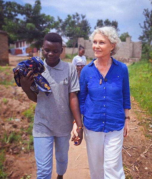 Eine junge tansanische Frau geht Hand in Hand mit einer älteren weißen Frau spazieren