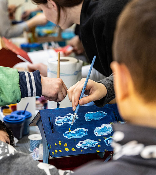 Kinder Malen einen Karton mit Wolken an