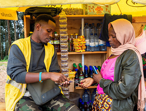 Ein Mann und eine Frau stehen vor einem Marktstand und tauschen Ware und Geld aus