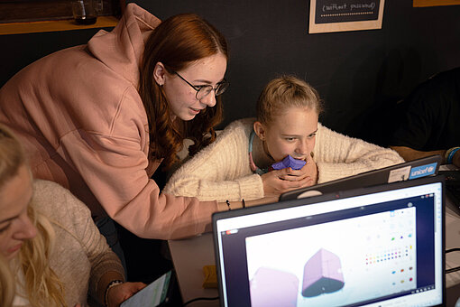 Eine junge Frau hilft einem Mädchen bei der Arbeit am Computer