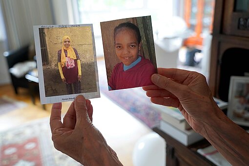 Christiane Böschen hält zwei Fotos ihres Patenkindes Marwa in die Kamera