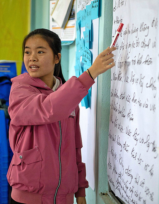 Ein Mädchen präsentiert Texte an einer Tafel