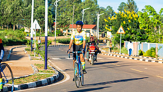 Eine junge Frau fährt im Fahrradtrikot und mit Helm auf einem Rennrad über eine Straße